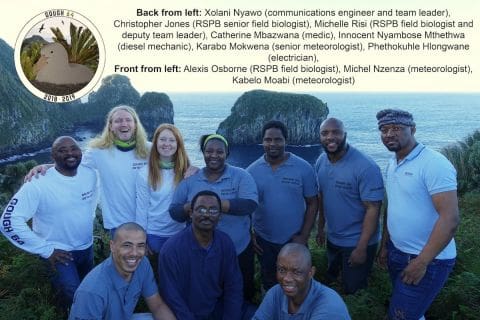 GOUGH 64 (2018-2019): Back (L-R) Xolani Nyawo (Communications Engineer/Team Leader), Christopher Jones (RSPB senior field biologist), Michelle Risi (RSPB field biologist/Deputy Team Leader), Catherine Mokotji Mbazwana (Medical orderly), Innocent Nyambose Mthethwa (Diesel Mechanic) ,Karabo Mokwena (Senior Meteorological Technician), Patrick (Phethokuhle) Hlongwane (Electrician); (front) Alexis Osborne (RSPB field biologist), Michel Nzenza (Meteorological Technician) and Kabelo Moabi (Meteorological Technician).